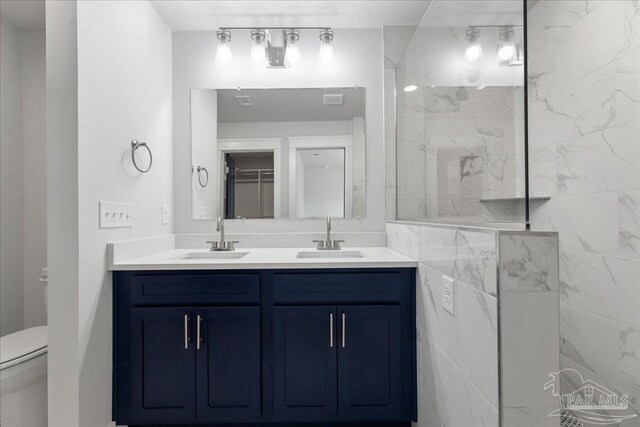 bathroom with double vanity, tile walls, and toilet