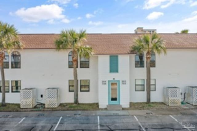 view of property featuring central AC unit and uncovered parking