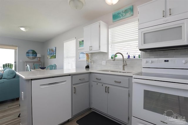 7464 Sunset Harbor Dr Unit 133, Navarre Beach, FL 32566 - kitchen featuring tasteful backsplash, sink, white cabinets, kitchen peninsula, and white appliances