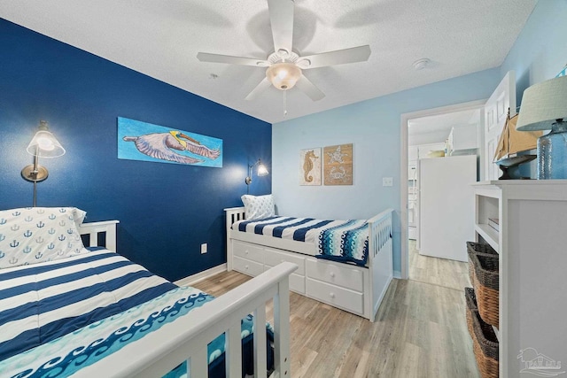 7464 Sunset Harbor Dr Unit 133, Navarre Beach, FL 32566 - bedroom with ceiling fan, white refrigerator, a textured ceiling, and light wood-type flooring