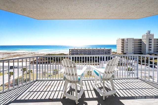 balcony with a water view and a view of the beach