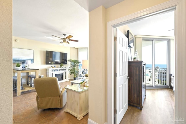 living room with ceiling fan, a wall of windows, and light hardwood / wood-style floors