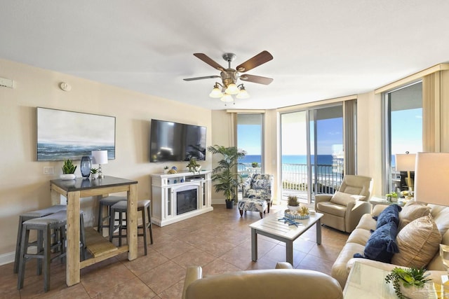 living room featuring ceiling fan, tile patterned flooring, and a wall of windows