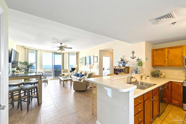 kitchen featuring a wall of windows, stainless steel appliances, sink, a kitchen breakfast bar, and kitchen peninsula