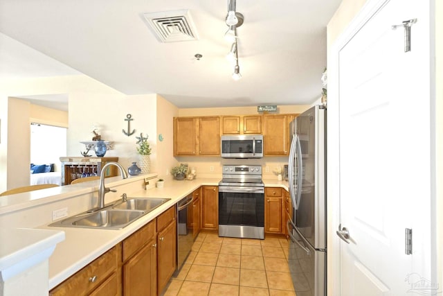 kitchen featuring light tile patterned floors, kitchen peninsula, sink, and stainless steel appliances