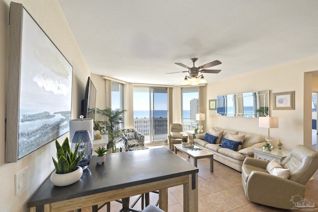 living room featuring ceiling fan, light tile patterned floors, and expansive windows