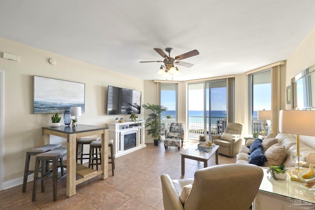 tiled living room featuring ceiling fan, plenty of natural light, and floor to ceiling windows