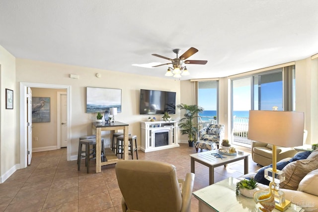 tiled living room featuring ceiling fan and a wall of windows