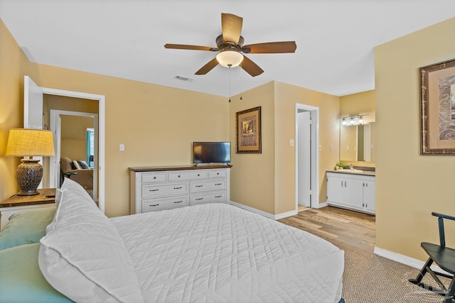 bedroom with ensuite bathroom, ceiling fan, and light hardwood / wood-style flooring