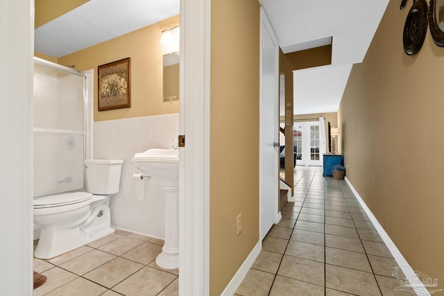 bathroom with tile walls, tile patterned floors, and toilet