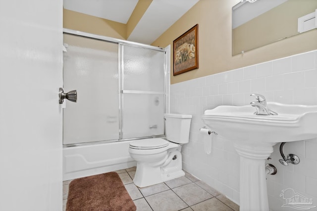 bathroom with tile walls, tile patterned flooring, enclosed tub / shower combo, and toilet