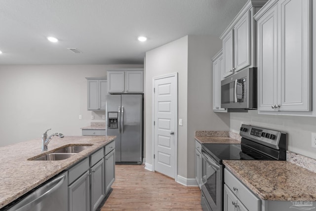 3594 Whitetail Ln, Pensacola, FL 32526 - kitchen featuring stainless steel appliances, light wood-style flooring, gray cabinetry, recessed lighting, and light stone countertops
