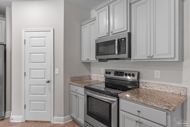 3594 Whitetail Ln, Pensacola, FL 32526 - kitchen featuring stainless steel appliances, light wood finished floors, gray cabinets, and light stone countertops