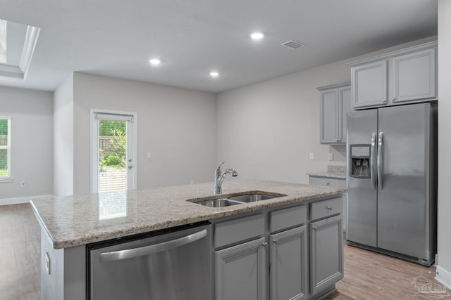 3594 Whitetail Ln, Pensacola, FL 32526 - kitchen featuring stainless steel appliances, light wood finished floors, gray cabinets, a center island with sink, and light stone counters