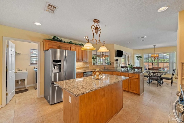 kitchen featuring light tile patterned floors, a center island, stainless steel appliances, and kitchen peninsula