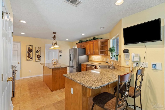 kitchen with decorative backsplash, appliances with stainless steel finishes, sink, kitchen peninsula, and a center island