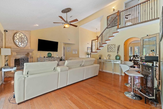 living room with a textured ceiling, high vaulted ceiling, ceiling fan, and wood-type flooring