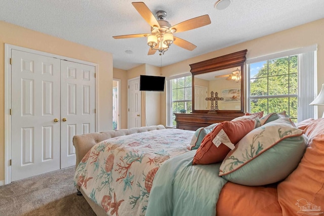 carpeted bedroom featuring ceiling fan and a textured ceiling