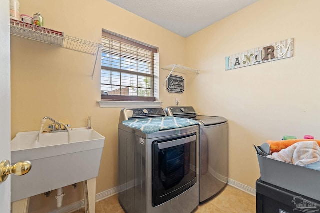 laundry area with sink, washing machine and clothes dryer, and light tile patterned flooring