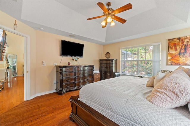 bedroom with a tray ceiling, ceiling fan, and hardwood / wood-style floors