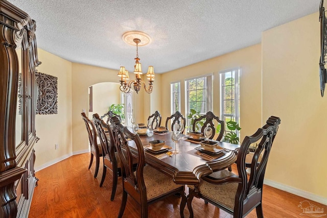 dining room with an inviting chandelier, light hardwood / wood-style flooring, and a textured ceiling