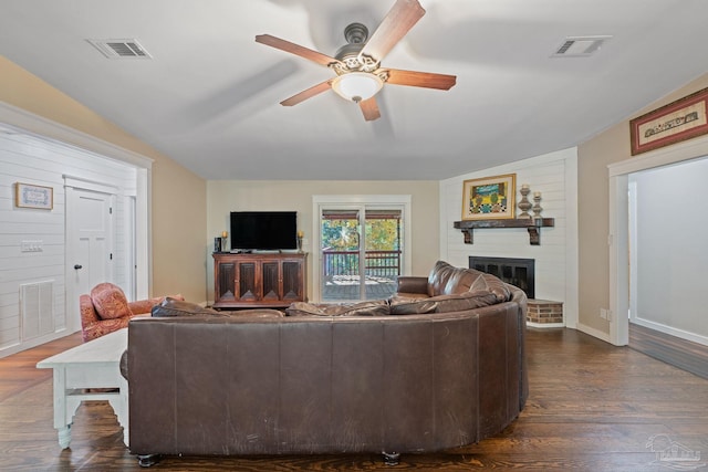 living room featuring ceiling fan, dark hardwood / wood-style flooring, lofted ceiling, and a brick fireplace