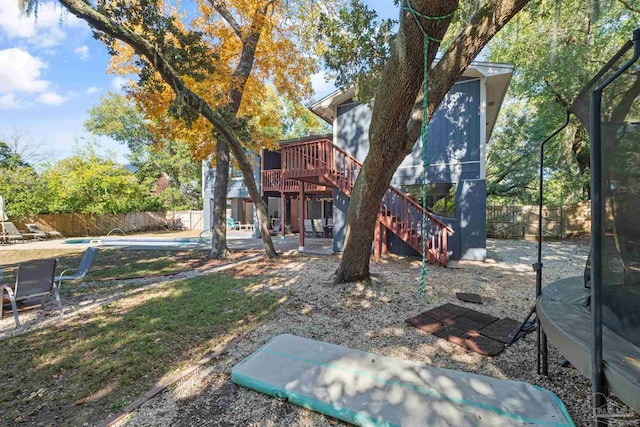 view of yard featuring a pool side deck, a patio area, and a trampoline