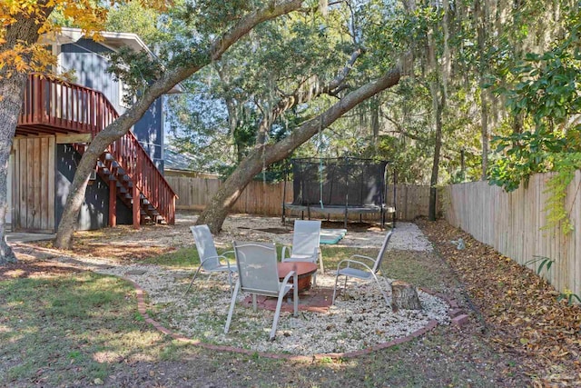 view of yard with a trampoline and a wooden deck