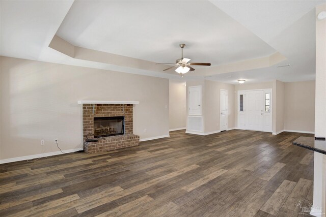 6459 E Quarry Dr, Elberta, AL 36530 - unfurnished living room featuring a tray ceiling, a ceiling fan, baseboards, wood finished floors, and a fireplace
