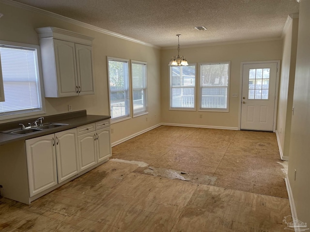 kitchen featuring white cabinetry, sink, hanging light fixtures, crown molding, and plenty of natural light