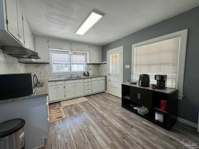 kitchen featuring white cabinets, sink, light wood-type flooring, and a textured ceiling