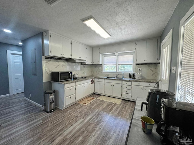 kitchen featuring white cabinetry, tasteful backsplash, a textured ceiling, wood-type flooring, and sink