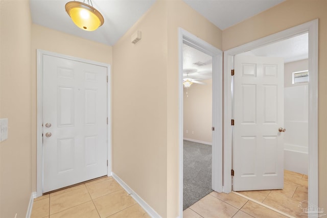 entrance foyer featuring light carpet, light tile patterned floors, baseboards, and a ceiling fan