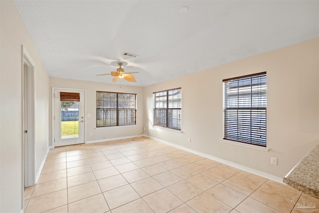 spare room with light tile patterned floors, baseboards, visible vents, and a ceiling fan