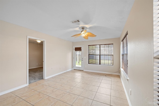 unfurnished room with a ceiling fan, visible vents, baseboards, and light tile patterned flooring