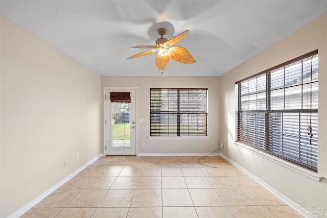 empty room featuring a ceiling fan, light tile patterned flooring, and baseboards