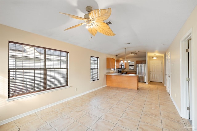 kitchen with light tile patterned floors, a peninsula, appliances with stainless steel finishes, and lofted ceiling