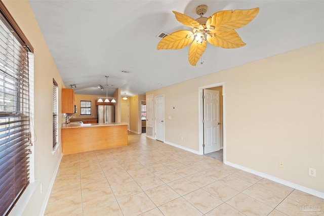 kitchen with light tile patterned floors, a peninsula, visible vents, vaulted ceiling, and freestanding refrigerator