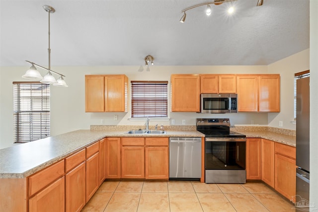 kitchen with a peninsula, light tile patterned floors, stainless steel appliances, and a sink