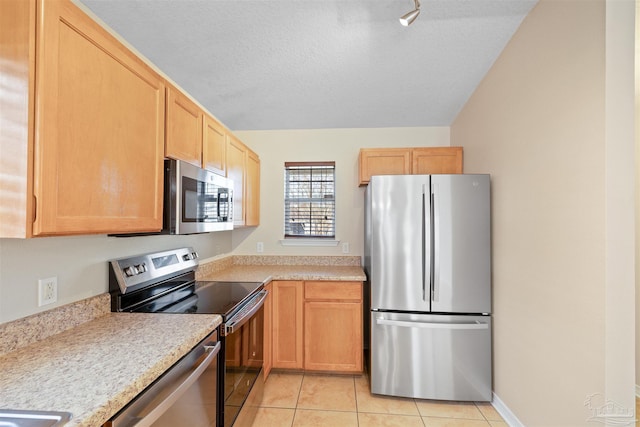 kitchen featuring light tile patterned floors, stainless steel appliances, a textured ceiling, light countertops, and light brown cabinets