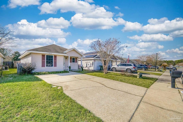 view of front facade with driveway, fence, and a front lawn