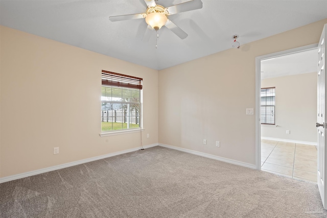 unfurnished room with a ceiling fan, light carpet, plenty of natural light, and baseboards