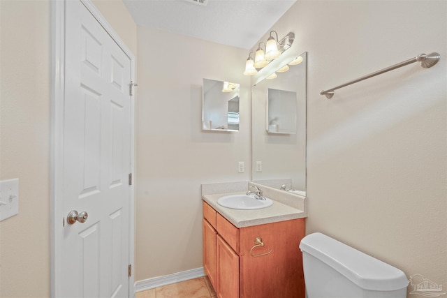 half bathroom featuring toilet, tile patterned floors, baseboards, and vanity