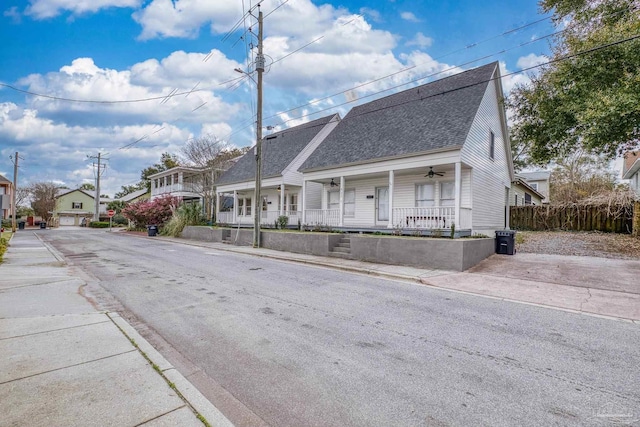 exterior space featuring covered porch, a residential view, fence, and roof with shingles