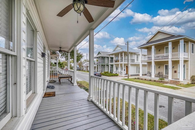 wooden terrace with covered porch, a residential view, and a ceiling fan