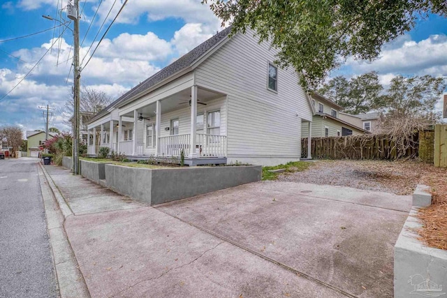 view of side of property featuring a porch, ceiling fan, and fence