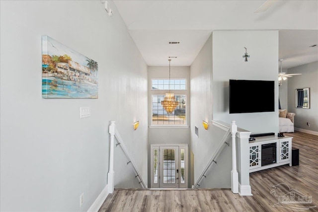 stairway with an inviting chandelier, hardwood / wood-style floors, and a high ceiling