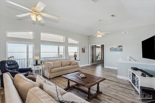 living room with a water view, ceiling fan, plenty of natural light, and hardwood / wood-style flooring