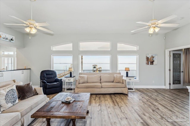 living room featuring wood-type flooring, ceiling fan, and vaulted ceiling