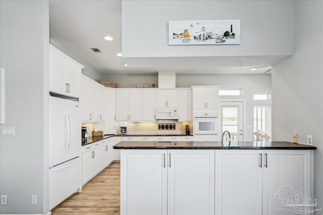 kitchen with white cabinetry, white appliances, kitchen peninsula, and backsplash